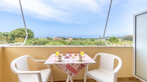 A balcony with a table set for two, two chairs, and a view of the countryside. - Apartment 'Lotus 4' with Shared Terrace, Wi-Fi and Air Conditioning (Corfu)