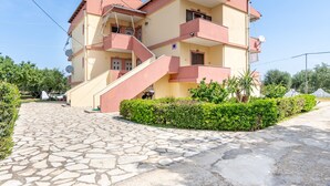 A multi-story building with a stone-paved entrance, balconies, and a clear sky. - Apartment 'Lotus 5' with Sea View, Wi-Fi and Air Conditioning (Corfu)