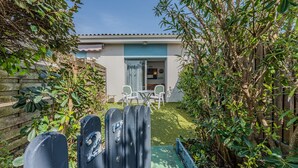 Una casa con un cortile recintato, un patio con sedie e un ingresso che conduce all'interno.