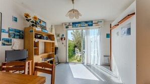 Una stanza con una scrivania in legno, sedie, un televisore, una libreria e un'ampia finestra vista su del verde.