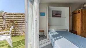 Una camera da letto con un letto a castello, un tavolino, una sedia, un ventilatore e vista sull'esterno.