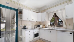 A kitchen with white cabinets, a microwave, a sink, and a dishwasher. - Villa 'El Chozo' with Sea View, Private Pool and Wi-Fi (Chiclana de la Frontera)