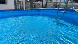 A clear blue swimming pool with a ladder, surrounded by trees and buildings. - Villa 'El Chozo' with Sea View, Private Pool and Wi-Fi (Chiclana de la Frontera)