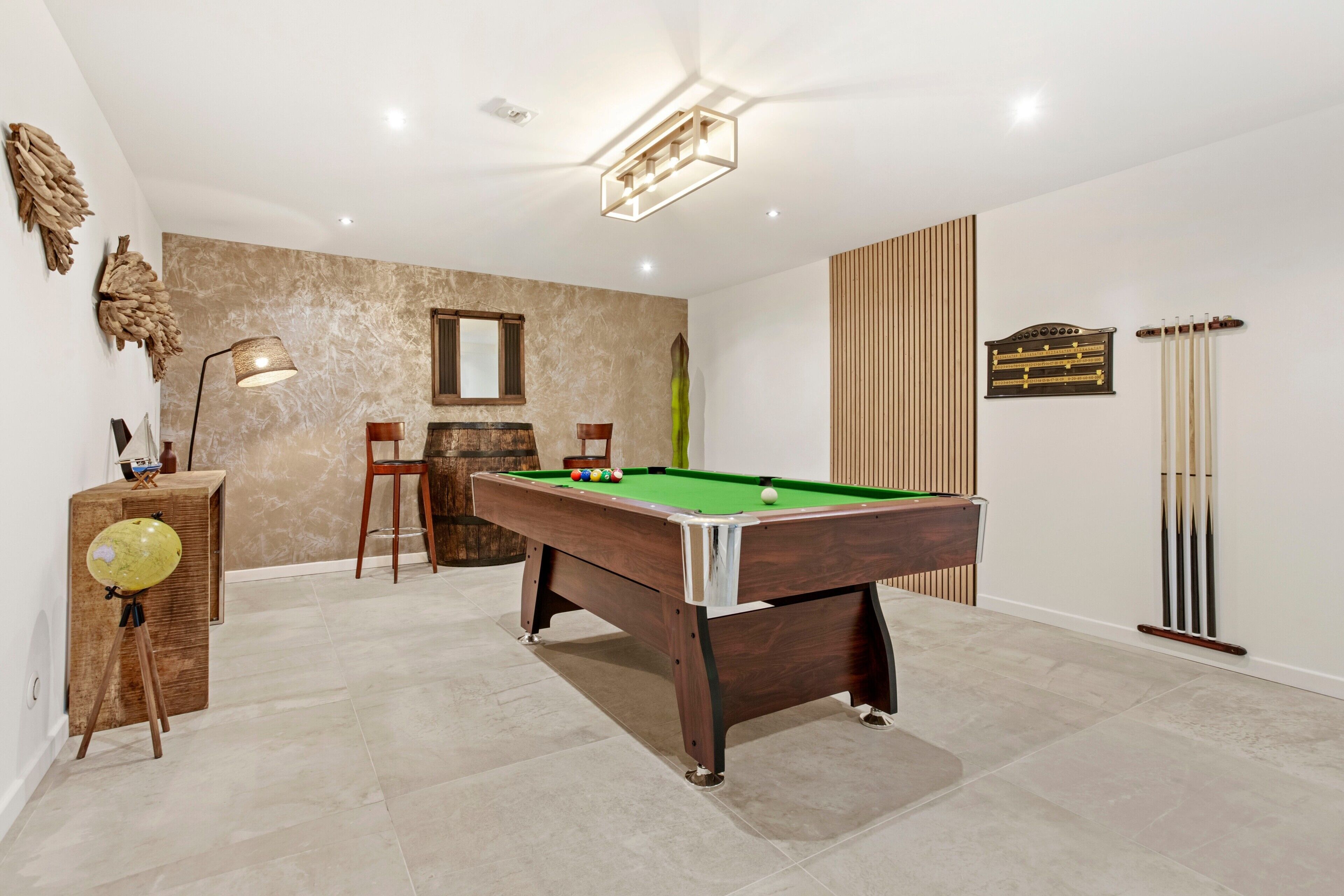 Une table de billard dans une pièce dotée d’un plancher en bois, d’un miroir et d’un porte-billes.