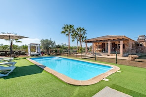 Piscina com cerca ao redor, alpendre coberto e um edifício de pedra.