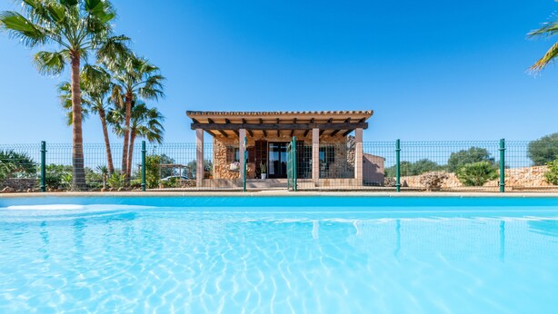 A pool with clear water, a covered pavilion, and palm trees in the background. - Country House 'Ses Oliveres' with Mountain View, Wi-Fi and Air Conditioning (Campos)