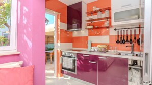 Une cuisine moderne avec des carreaux violets et orange, des appareils en acier inoxydable et une fenêtre donnant sur un patio.