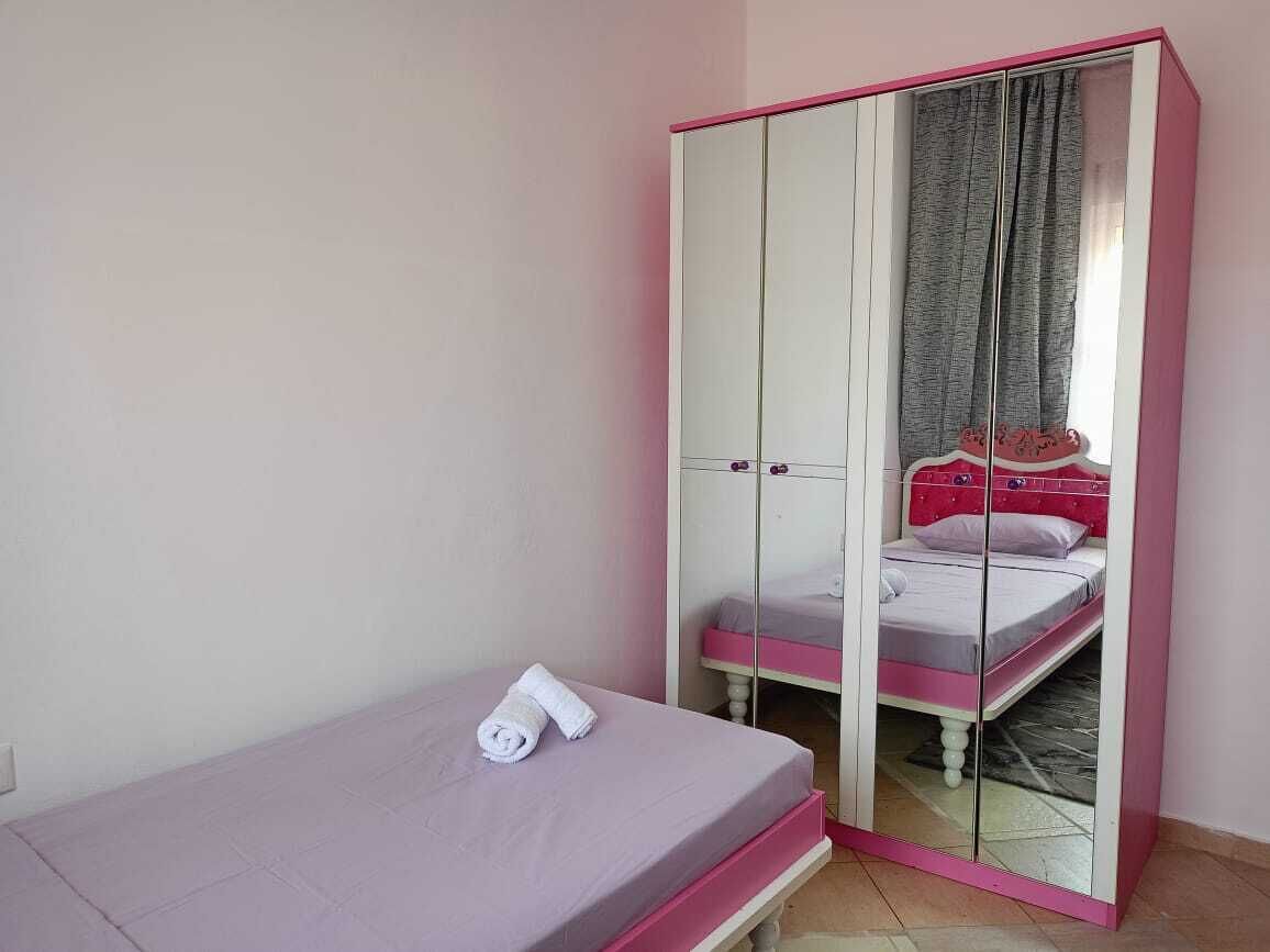 Una camera da letto con un letto, un armadio rosa e bianco e uno specchio.