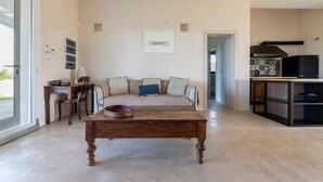Een moderne woonkamer met een bank, salontafel en een keukenhoek met fornuis en kasten.