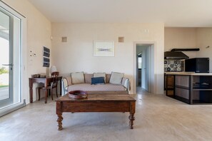 Un salon moderne comprenant un canapé, une table basse et un coin cuisine avec une cuisinière et des placards.