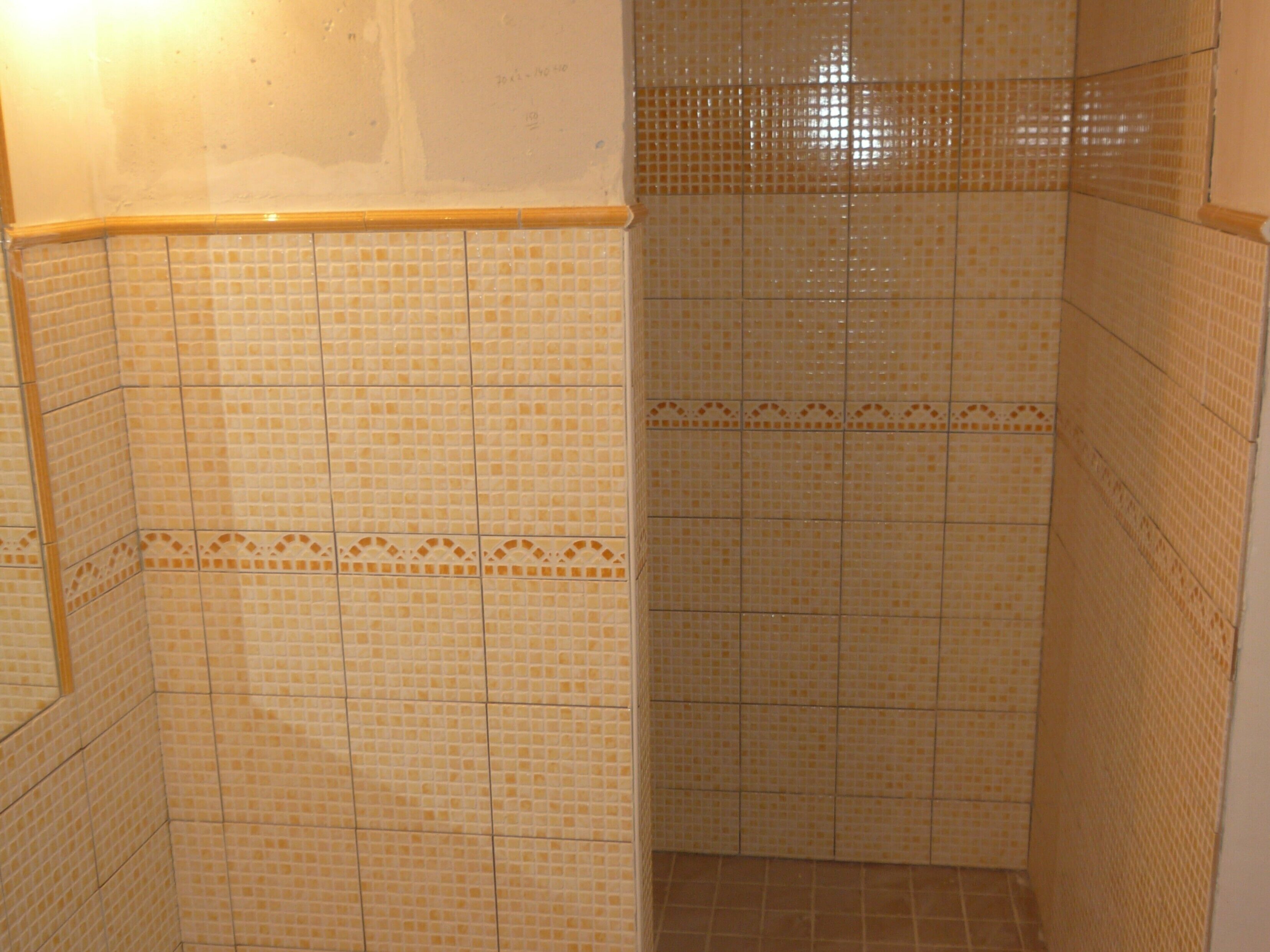 A tiled shower enclosure with a corner design, a visible door frame, and a tiled floor.