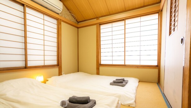 A traditional Japanese room with tatami flooring, two beds with white bedding, and sliding shoji doors.