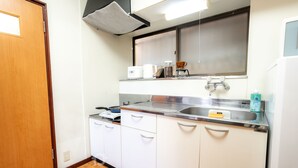 A compact kitchen with white cabinets, a stainless steel sink, and a coffee maker.