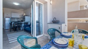 A compact living space with a kitchen, dining area, and a balcony with a table set for dining. - 'Ad Occhi Aperti - Castelsardo' Apartment with Sea View, Wi-Fi, and Air Conditioning (Castelsardo)