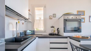A modern kitchen with a built-in oven, a microwave, and a sink. - 'Ad Occhi Aperti - Castelsardo' Apartment with Sea View, Wi-Fi, and Air Conditioning (Castelsardo)