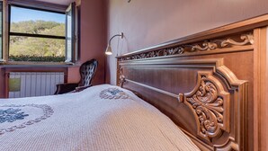 A bedroom with a large window, a bed with a decorative headboard, a bedside lamp, and a view of the outdoors. - Farmhouse 'Agriturismo Il Ponte - Frantoio' with Mountain View, Private Garden and Wi-Fi (Vicchio)