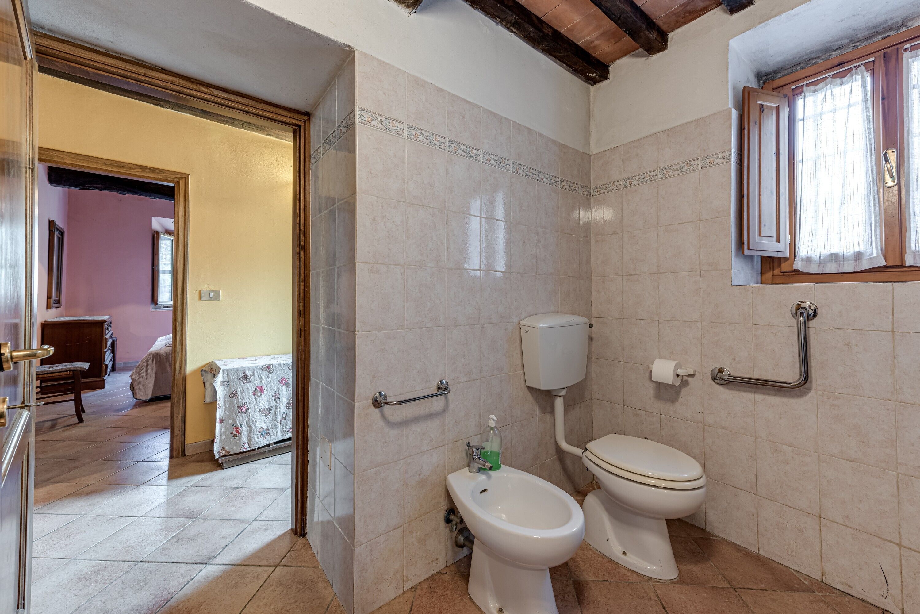 Une salle de bain équipée de toilettes, d’un bidet et de barres d’appui.