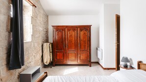 A bedroom with a bed, a wooden wardrobe, a radiator, and a nightstand with a lamp. - Holiday Home 'La Rétaise' with Private Terrace and Garden (Romegoux)