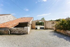 A building with a red-tiled roof, a gravel driveway, and an arched entrance. - Holiday Home 'L'Aixoise' with Private Terrace, Private Garden and Wi-Fi (Romegoux)