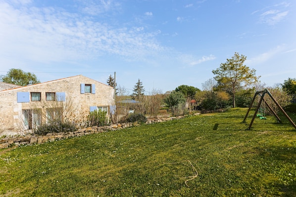 A stone house with a grassy yard and a swing set.