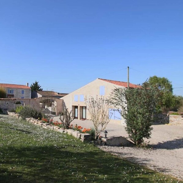 A residential property with a garden, a stone wall, and a building with a tiled roof.