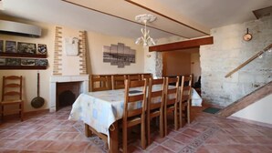 Ein Essbereich mit einem für sechs Personen gedeckten Tisch, Holzsesseln, einem Kamin und einer Steinwand.