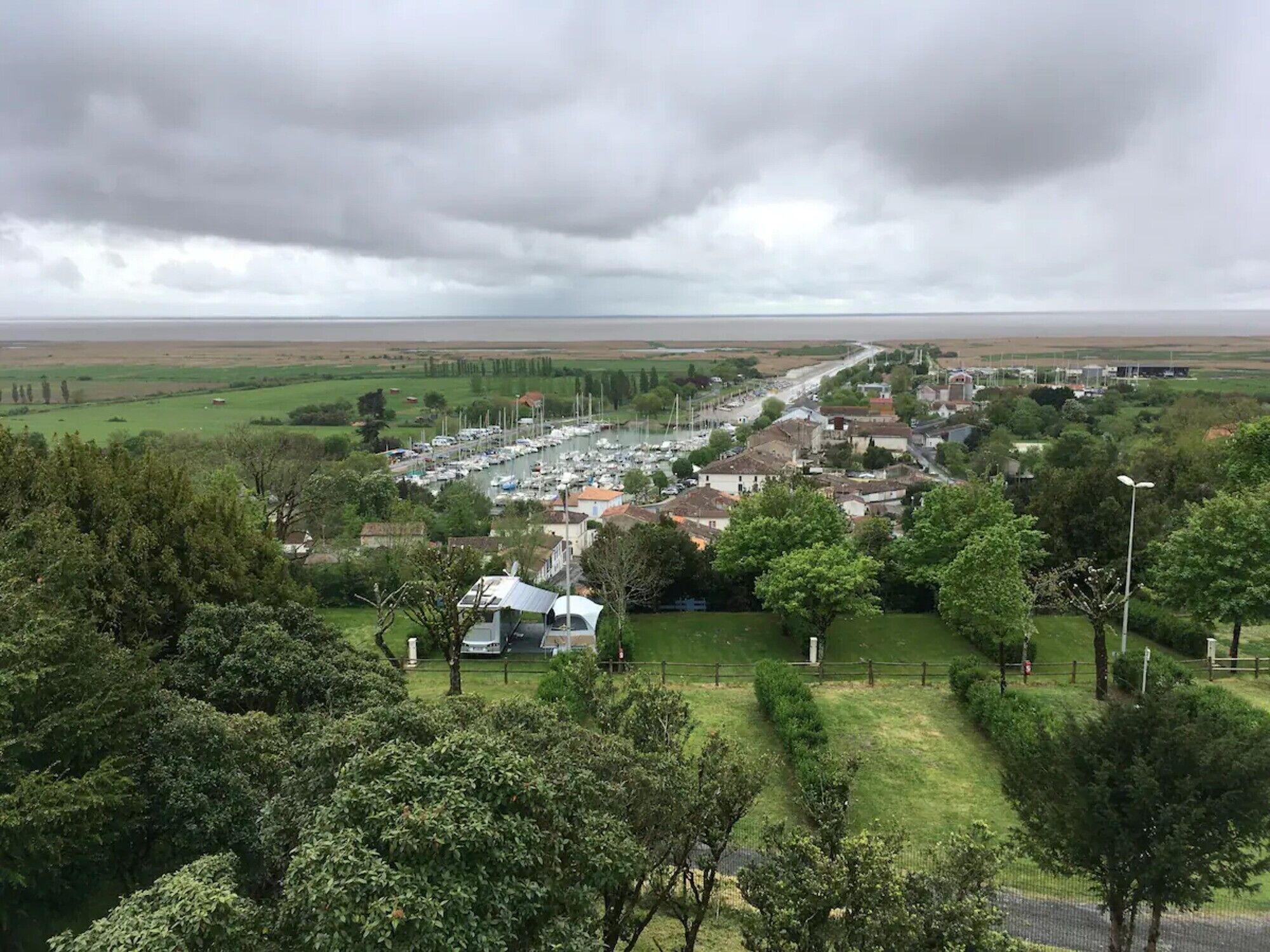 A coastal town with a marina, houses, and green fields.