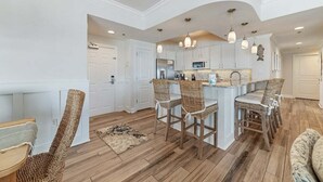 A spacious kitchen with white cabinetry, a central island with bar stools, and pendant lighting.