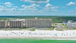 A beachfront hotel with multiple buildings, a sandy beach, and a clear sky.