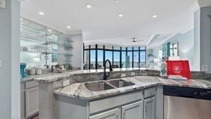 A modern kitchen with a large island, built-in appliances, and a view to the outside.