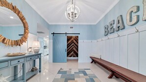 A hallway with a blue wall, a wooden bench, a chandelier, and a patterned rug. - ULTRA LUXURY BEACHFRONT CONDO, 3500SQFT, CUSTOM EVERYTHING (Orange Beach)