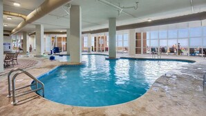 An indoor swimming pool with clear water, surrounded by large windows and a tiled floor. - ULTRA LUXURY BEACHFRONT CONDO, 3500SQFT, CUSTOM EVERYTHING (Orange Beach)