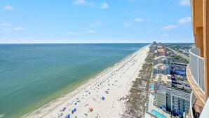A beach with a long stretch of sand and a row of buildings along the shore. - ULTRA LUXURY BEACHFRONT CONDO, 3500SQFT, CUSTOM EVERYTHING (Orange Beach)