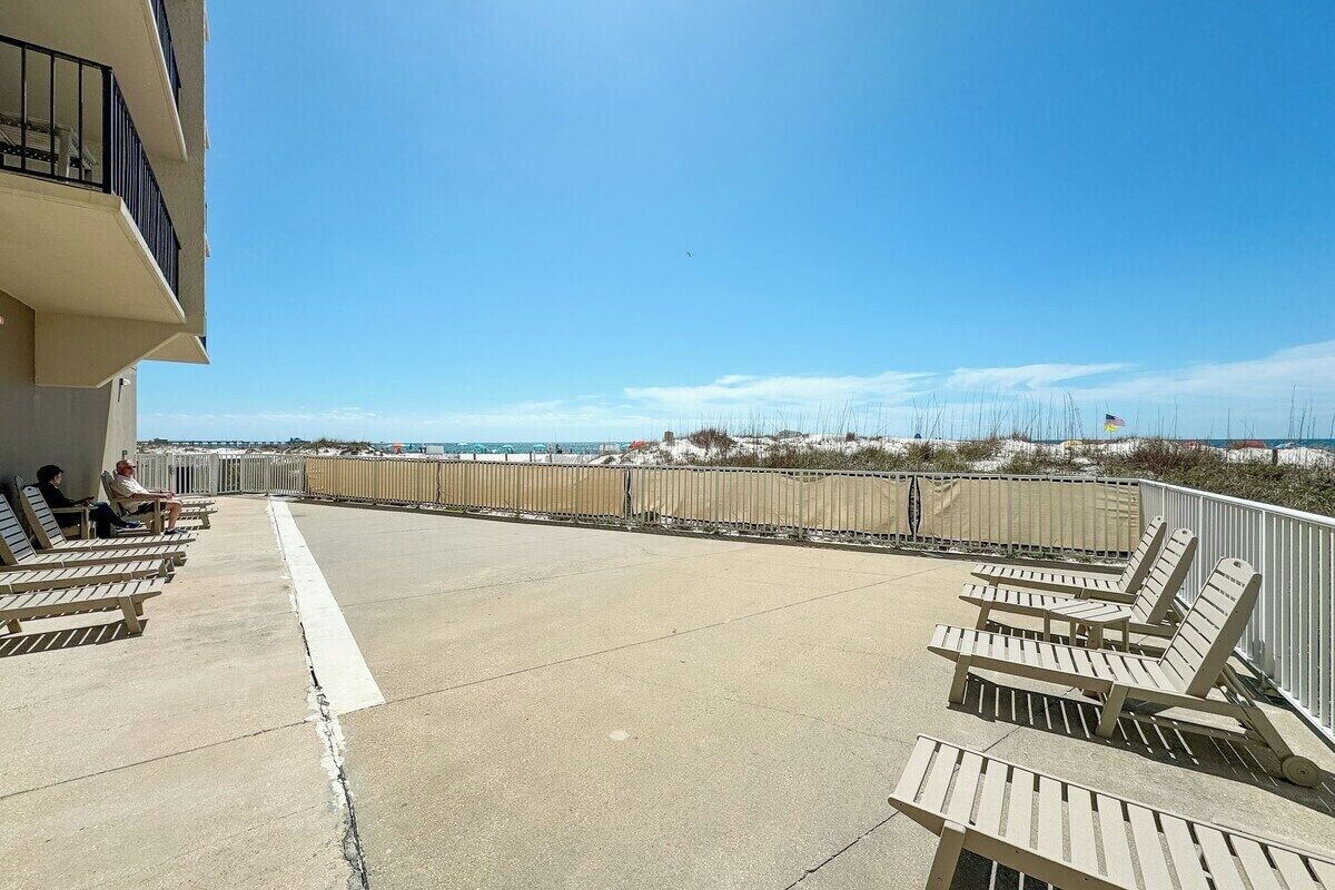 Un balcon avec des fauteuils de jardin donnant sur une plage.