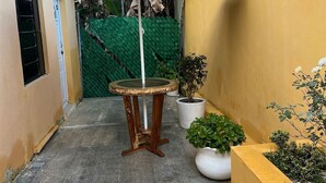 A small outdoor area with a round wooden table and a blue umbrella. - Kiimakóol  (Coba)