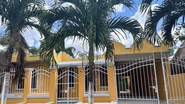A yellow house with white decorative elements and a gated entrance. - Kiimakóol  (Coba)