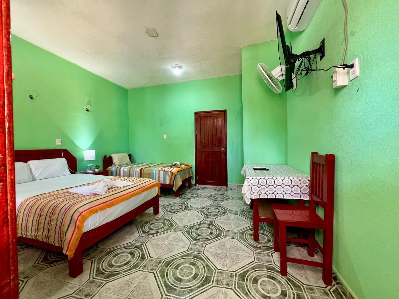 A room with two beds, a table, and a chair.