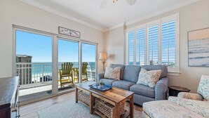 A living room with a sofa, a coffee table, and a view of the ocean through large windows. - AMAZING CORNER UNIT, HUGE POOLS, BEACH VIEWS - Crystal Tower 809 (Gulf Shores)