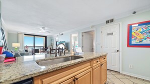 A kitchen with granite countertops, wooden cabinets, and a built-in dishwasher. - BEACHFRONT, FAMILY FRIENDLY, LOW FLOOR, OUTDOOR POOL (Orange Beach)