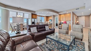A spacious living area with a brown leather sofa, patterned armchairs, and a glass coffee table. - WATERFRONT LOW DENSITY CONDO, BEACH ACCESS, INDOOR/OUTDOOR POOLS (Gulf Shores)