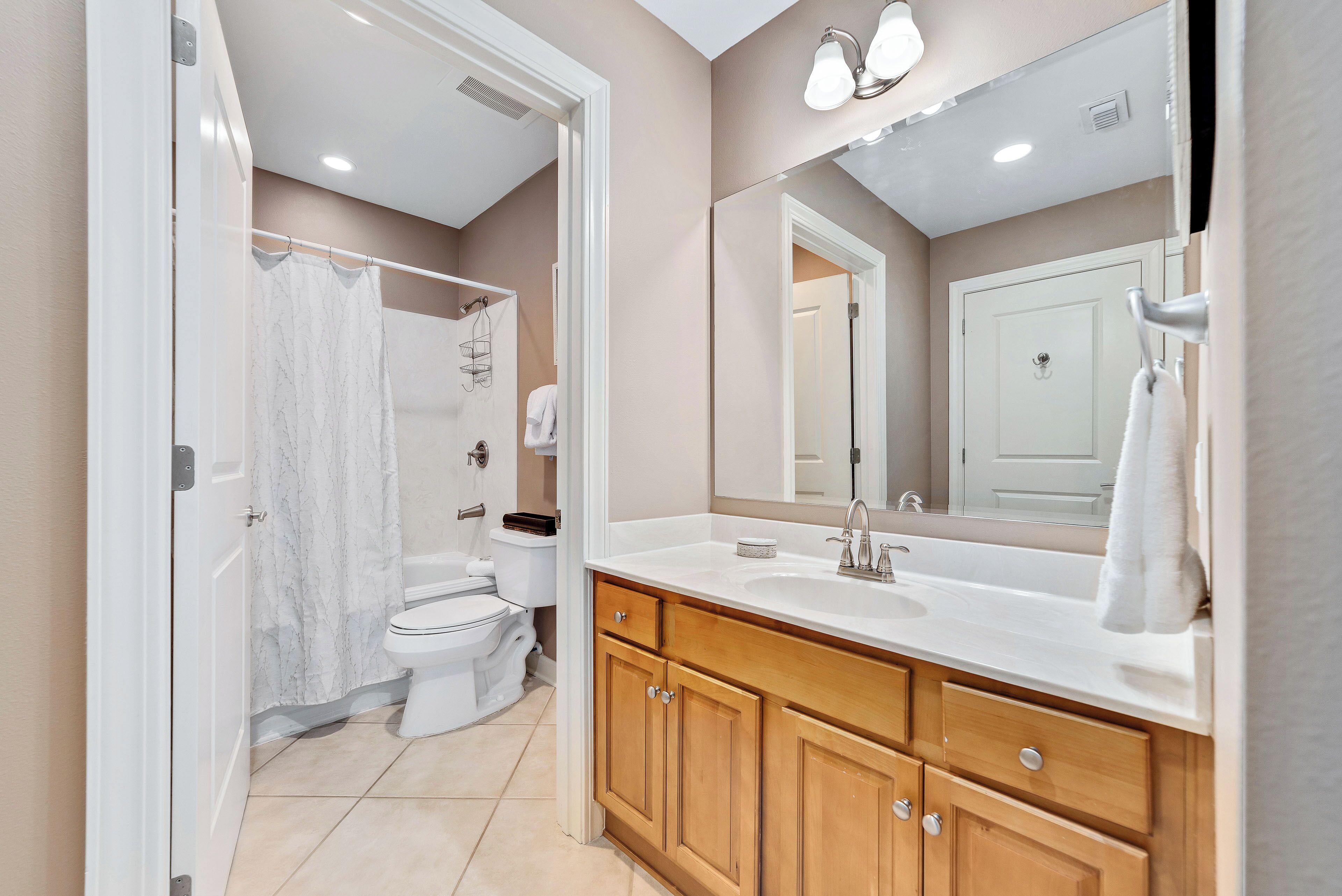 Une salle de bain moderne avec un lavabo blanc, un meuble-lavabo en bois et un grand miroir.
