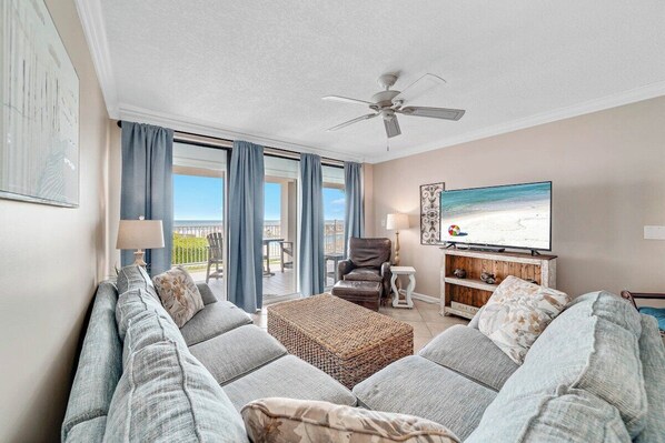 A living room with a sofa set, a television, and a ceiling fan.