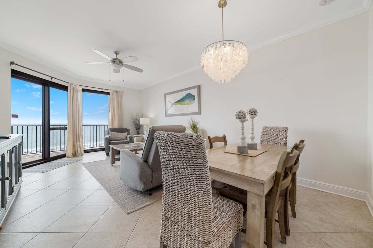 A dining area with a wooden table, wicker chairs, and a chandelier.
