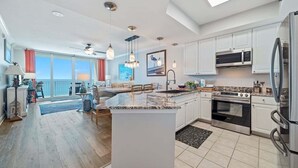 A spacious kitchen with white cabinets, a large island, stainless steel appliances, and pendant lighting. - BEACHFRONT, FAMILY FRIENDLY, OUTDOOR POOL, CLOSE TO RESTAURANTS (Gulf Shores)