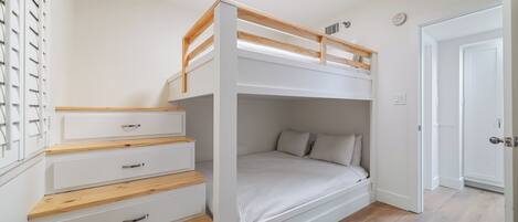 Un letto a castello con testiera in legno, cassetti bianchi e materasso bianco.