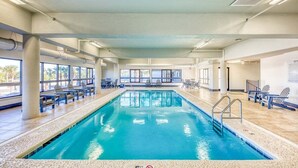An indoor swimming pool with clear blue water, surrounded by lounge chairs and a tiled floor. - BEACHFRONT, FAMILY FRIENDLY, LOW FLOOR, INDOOR/OUTDOOR POOL (Orange Beach)
