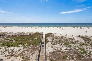 A beach with a wooden boardwalk leading to the shore, sandy dunes, and beach umbrellas.