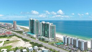 A coastal cityscape with high-rise buildings, a beach, and a clear blue sky. - BEACHFRONT, FAMILY FRIENDLY, LOW FLOOR, INDOOR/OUTDOOR POOL (Orange Beach)