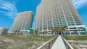 Een modern hoog hotel met een gebogen gevel, meerdere balkons en een ligging aan het strand.