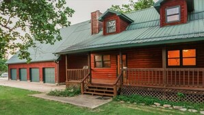 A wooden log cabin with a metal roof, a porch, and a small window.